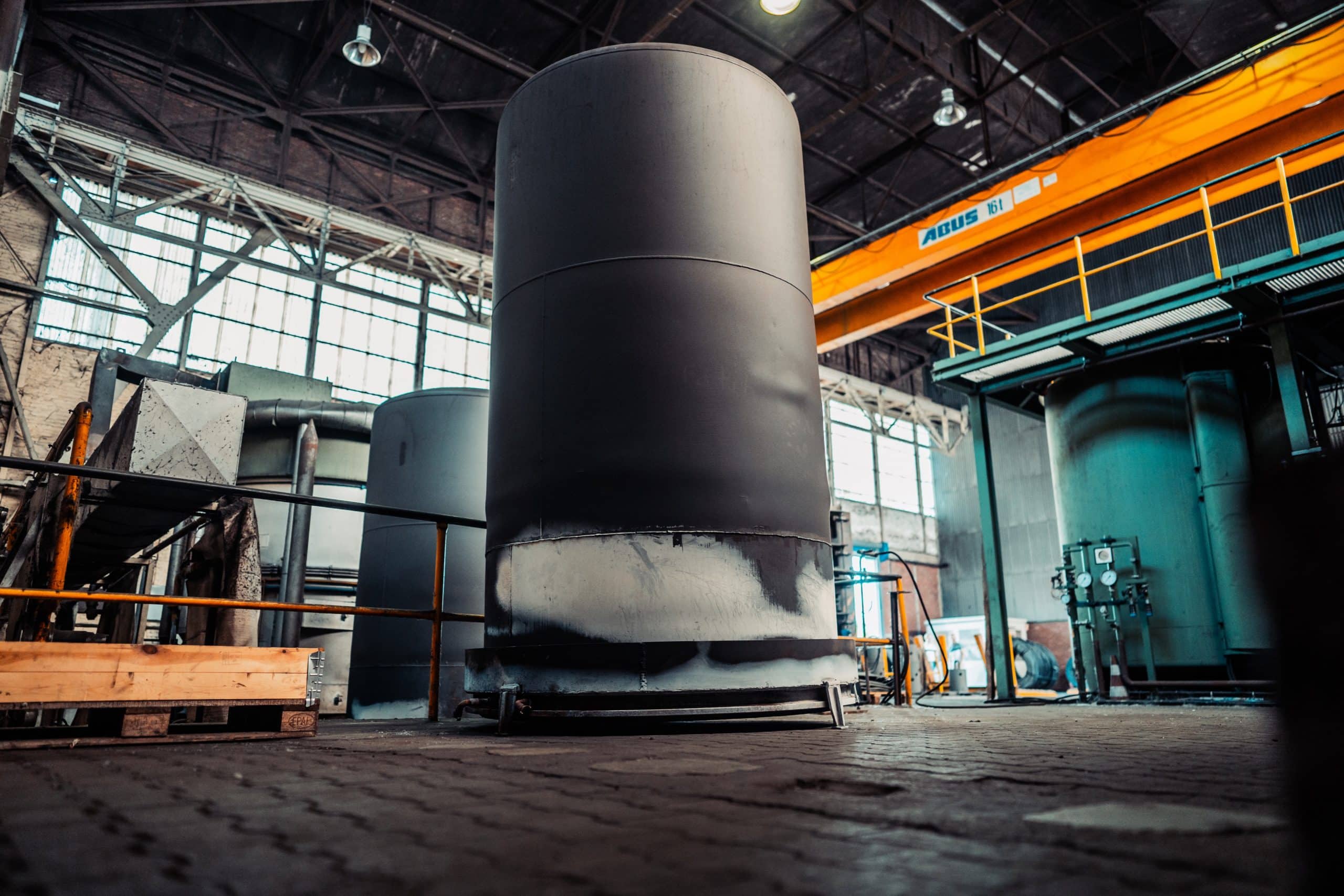 Ein großes Silo (Retorte) steht in einer Industriehalle. Es ist von außen am unteren Bereich von thermischen Einflüssen beinflusst.